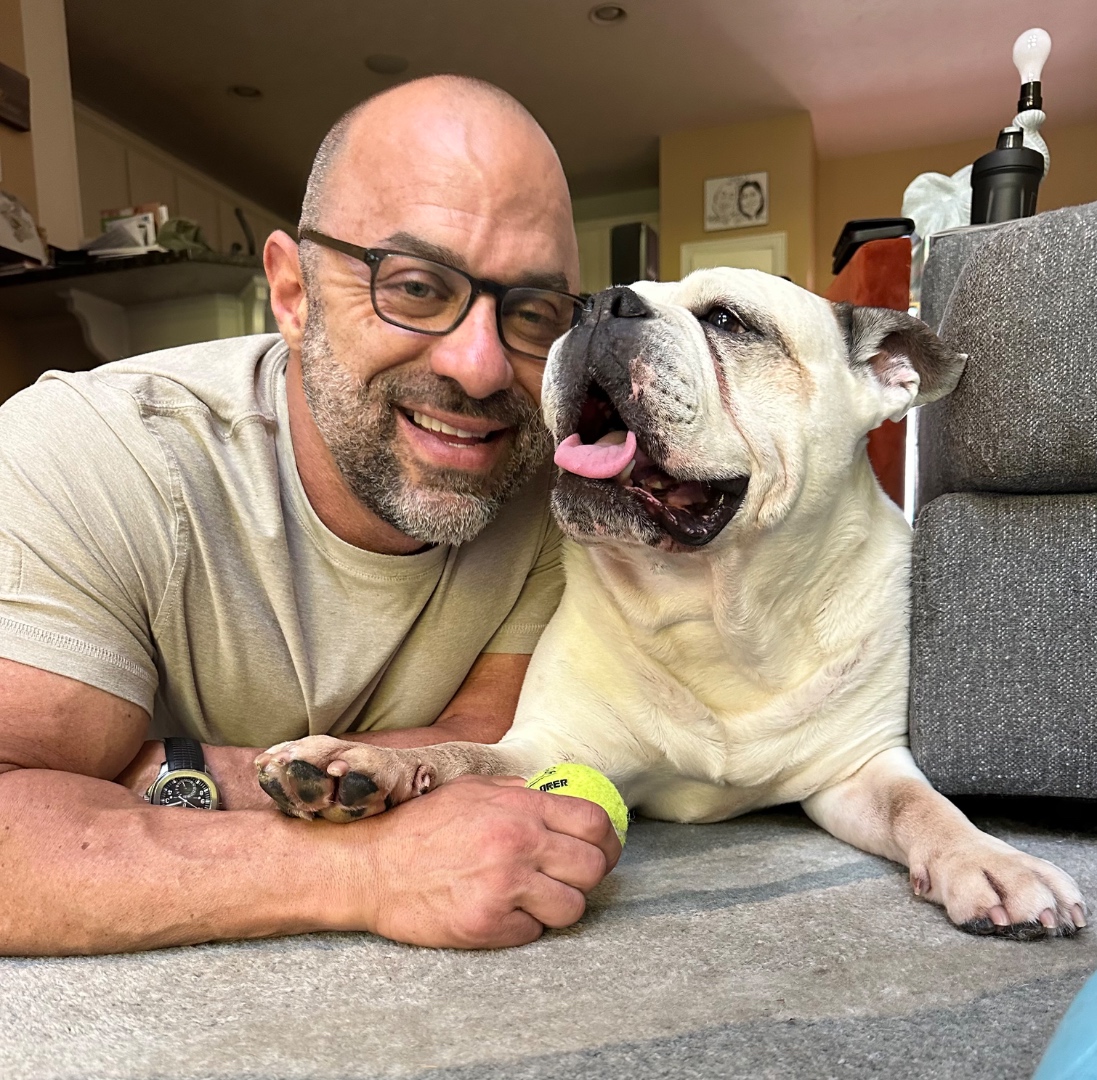 Anthony Castore smiling next to Jeter, his English bulldog.